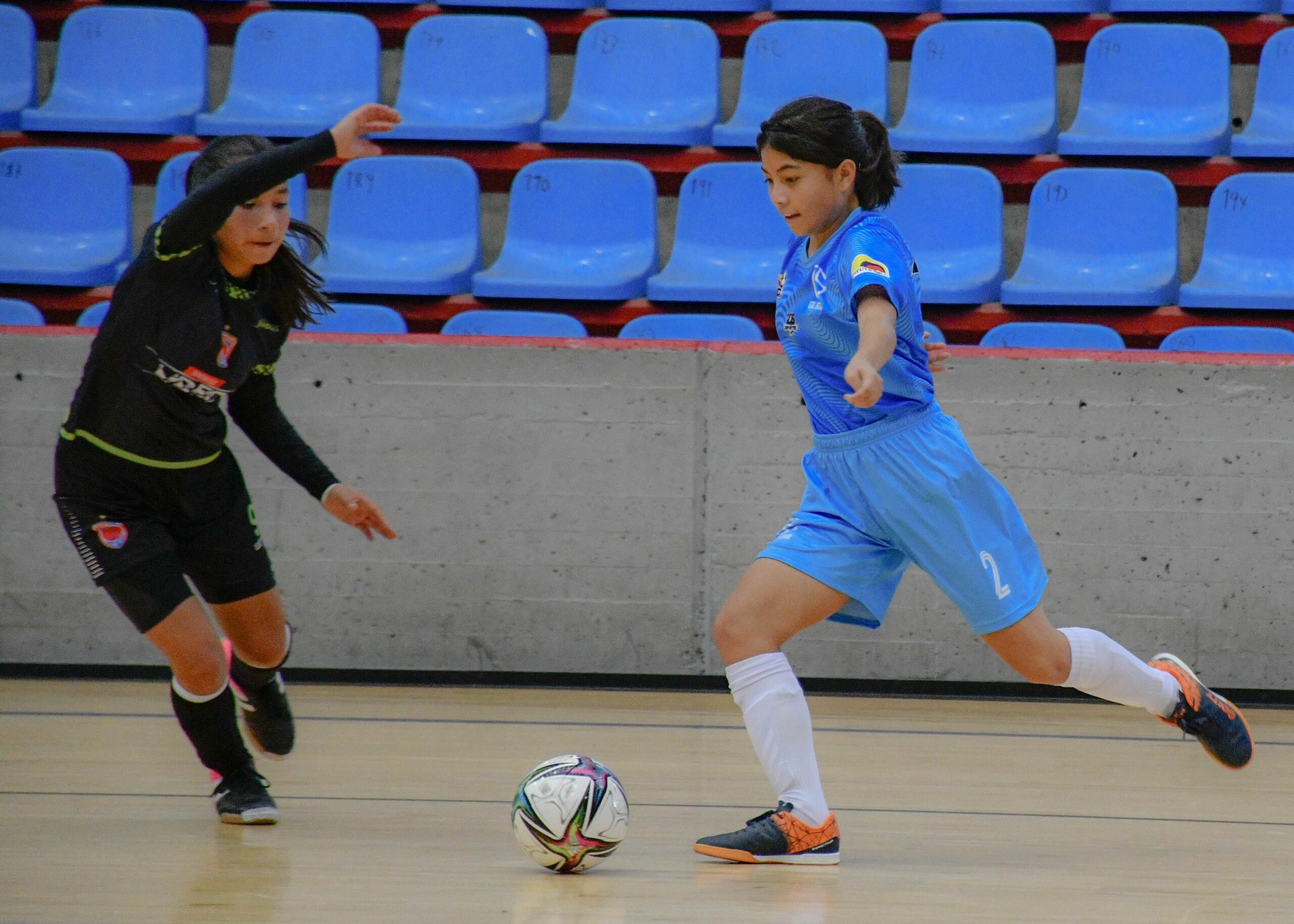 Deux joueuses de futsal en duel pour le ballon dans une salle