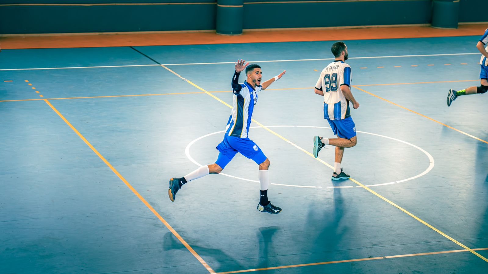 Joueurs de futsal en action sur un terrain en salle