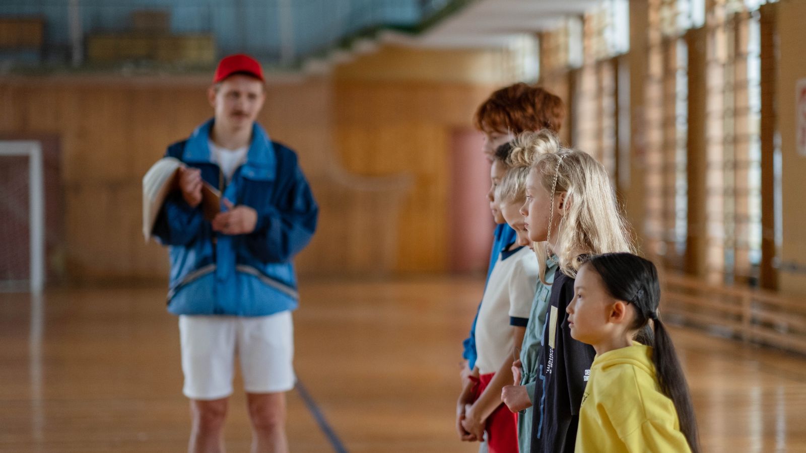 Groupe d enfants aligne devant leur educateur dans un gymnase